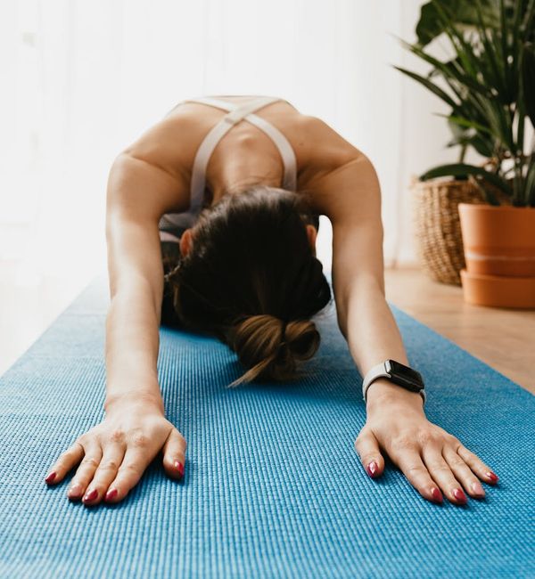 Woman in a peaceful yoga pose, sunlight illuminating the room.